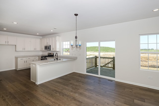 kitchen with a peninsula, dark wood-style floors, light countertops, white cabinets, and appliances with stainless steel finishes