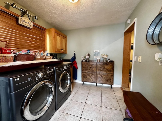 washroom with a textured ceiling, washing machine and dryer, cabinet space, and light tile patterned flooring