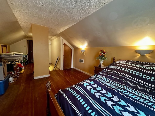 bedroom with a textured ceiling, visible vents, baseboards, lofted ceiling, and hardwood / wood-style floors