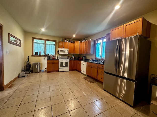 kitchen featuring white appliances, dark countertops, a sink, and a wealth of natural light