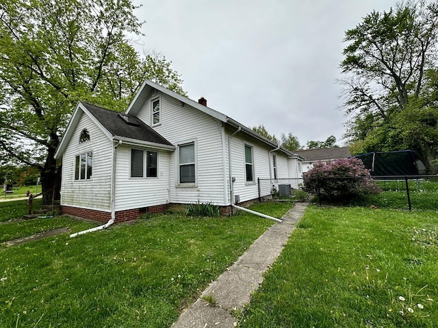 view of side of home featuring fence, central air condition unit, a chimney, and a lawn