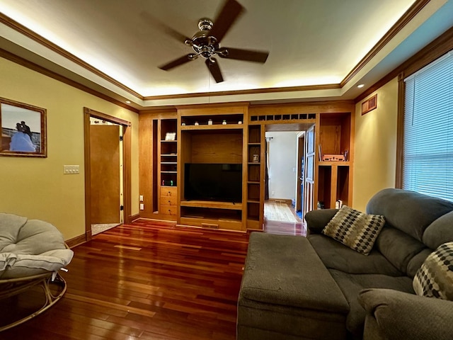 living area with crown molding, a raised ceiling, and ceiling fan