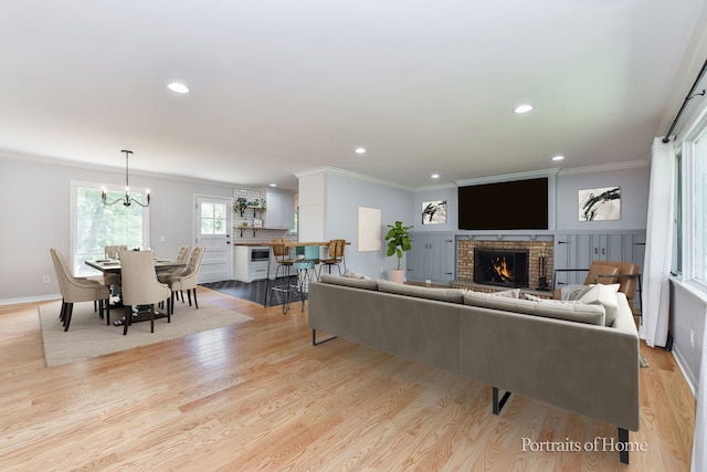 232 S Randall Rd, Aurora, IL 60506 - living room featuring ornamental molding, a brick fireplace, light wood-style flooring, recessed lighting, and a chandelier