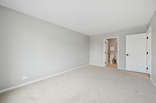 unfurnished bedroom featuring baseboards, light carpet, and ensuite bath