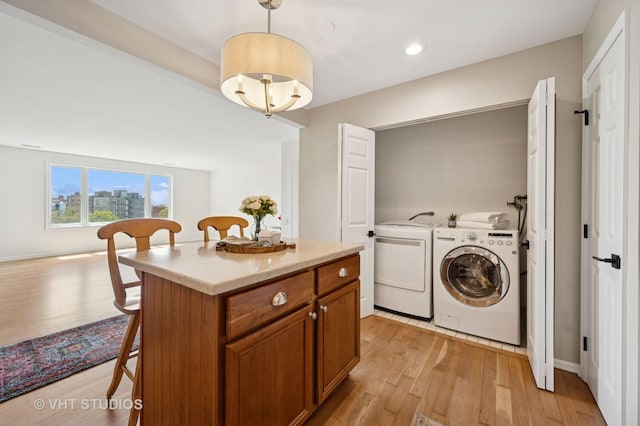clothes washing area with separate washer and dryer, light wood-type flooring, and recessed lighting