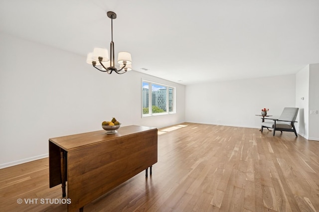 dining space with light wood-style flooring, a chandelier, and baseboards