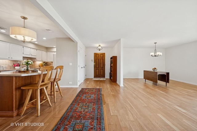 foyer entrance with light wood-style floors, baseboards, a chandelier, and recessed lighting