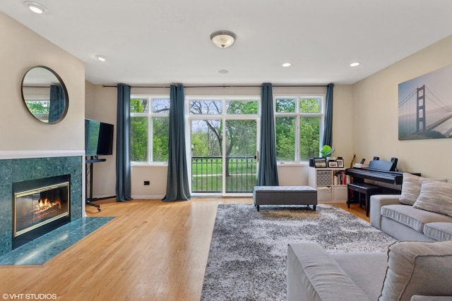 living area featuring a fireplace, recessed lighting, baseboards, and wood finished floors