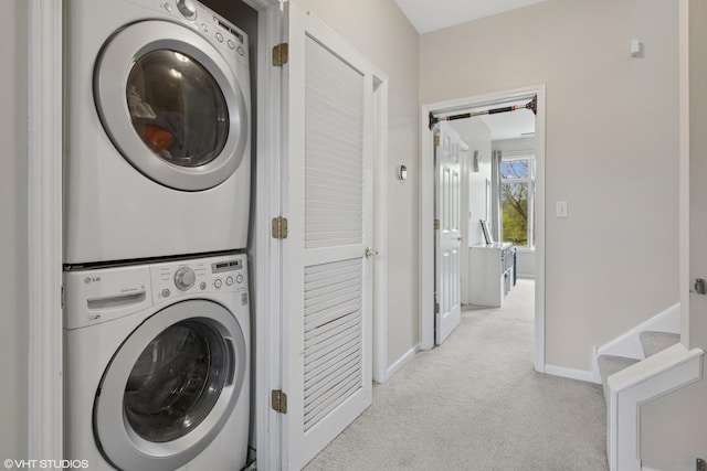 washroom with baseboards, stacked washer and dryer, laundry area, and light colored carpet