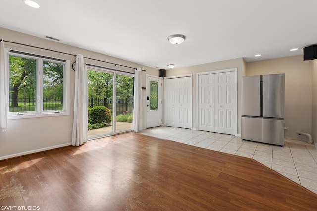 unfurnished bedroom with access to exterior, freestanding refrigerator, multiple closets, visible vents, and baseboards