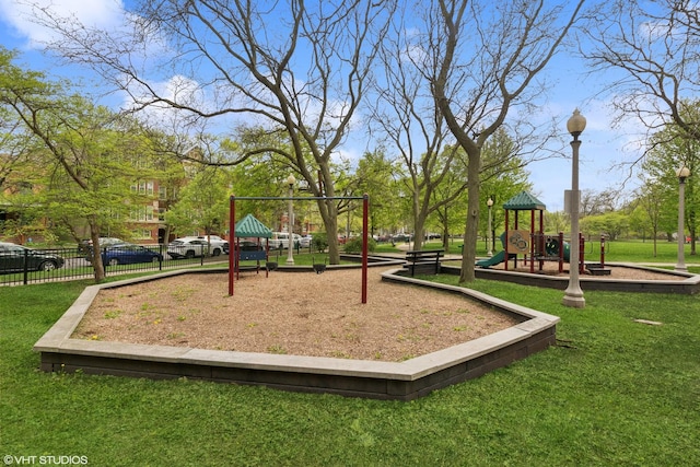 view of property's community with fence, playground community, and a lawn