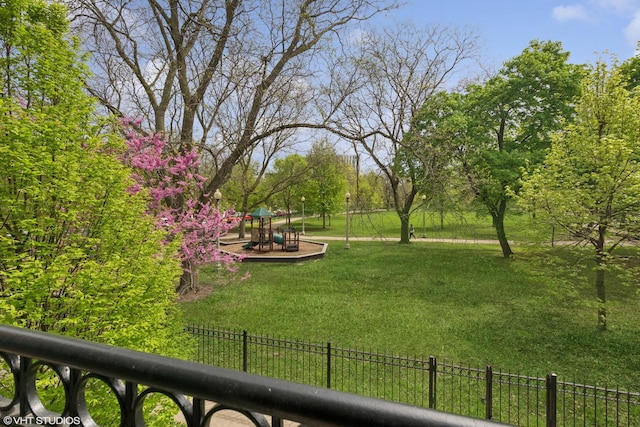 view of community featuring a lawn, a playground, and fence