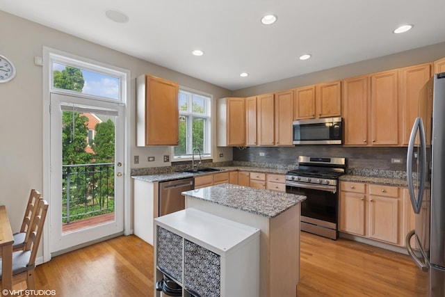 kitchen featuring a sink, light wood finished floors, light brown cabinetry, and appliances with stainless steel finishes