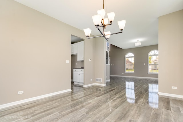 unfurnished room featuring a chandelier, baseboards, visible vents, and light wood finished floors