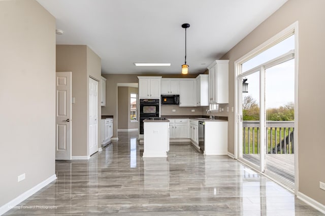 kitchen with hanging light fixtures, a sink, baseboards, black appliances, and white cabinetry