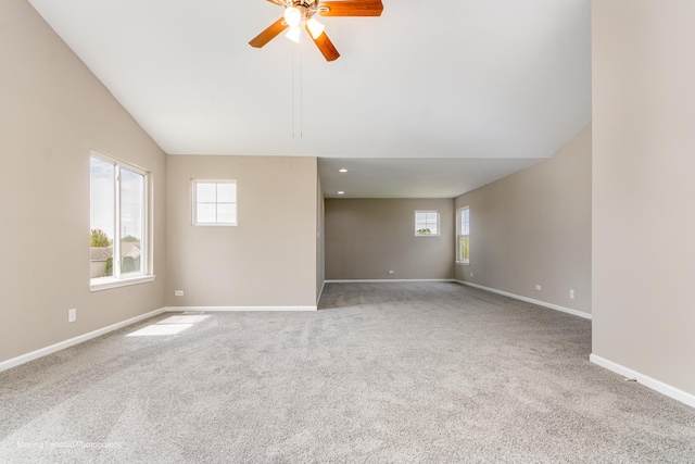 carpeted empty room featuring baseboards, ceiling fan, a wealth of natural light, and lofted ceiling