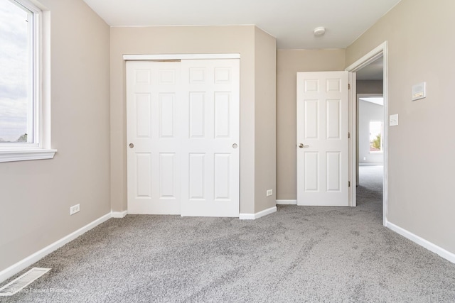 unfurnished bedroom featuring a closet, baseboards, carpet flooring, and visible vents