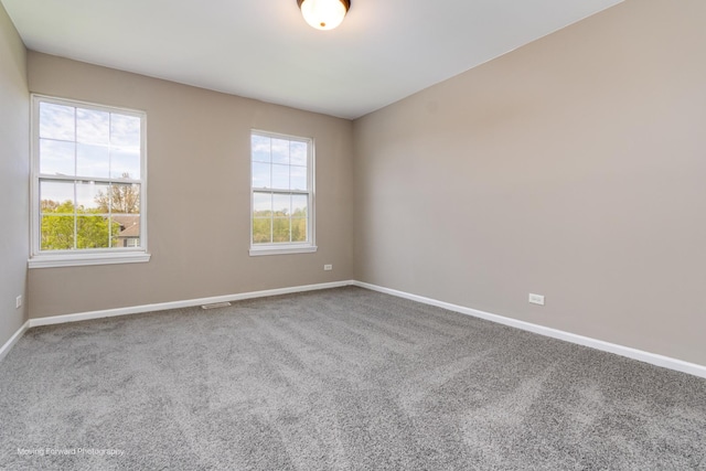 carpeted spare room featuring baseboards and visible vents