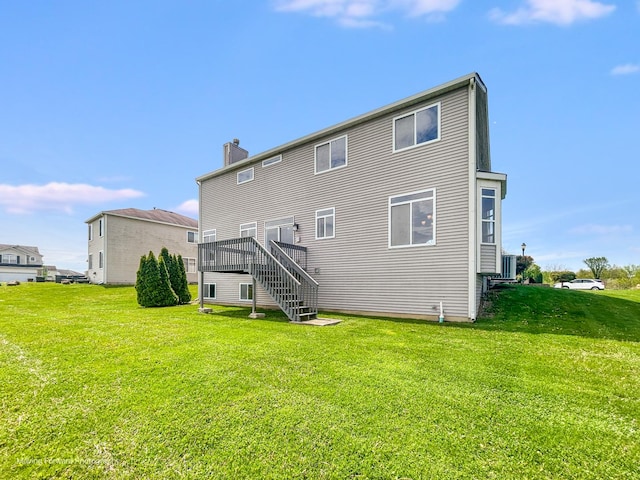 rear view of property with a chimney, central AC unit, a yard, and stairway
