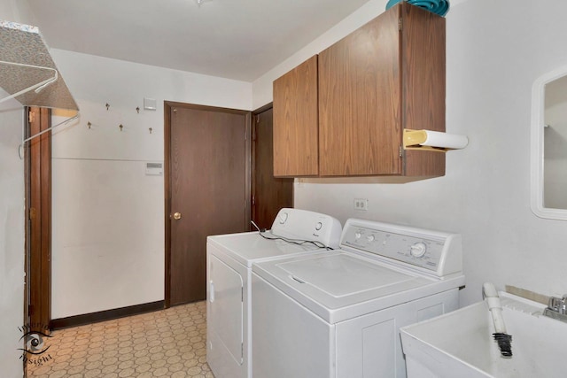 clothes washing area featuring light floors, a sink, cabinet space, and washing machine and clothes dryer