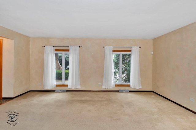 unfurnished room featuring baseboards, visible vents, carpet flooring, and a wealth of natural light