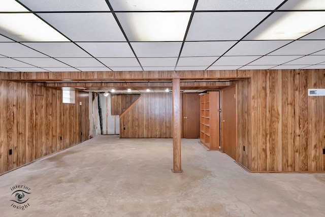 finished below grade area featuring wooden walls and a paneled ceiling