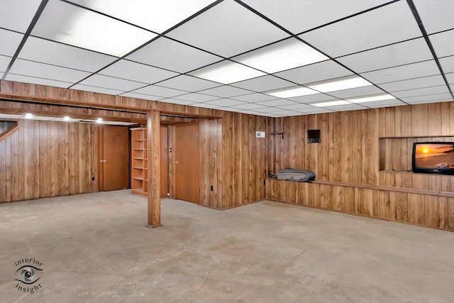finished basement with wood walls and a paneled ceiling