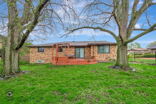 rear view of house with fence, a lawn, and brick siding
