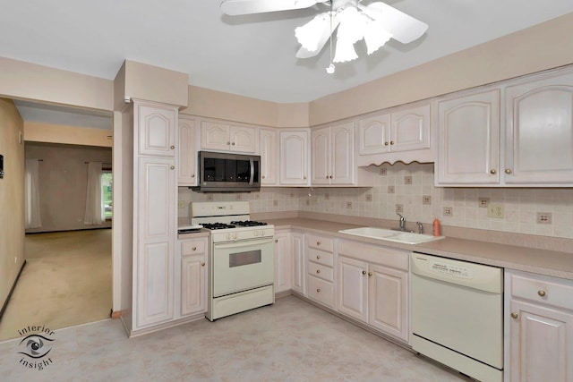 kitchen with white appliances, decorative backsplash, a sink, and light countertops