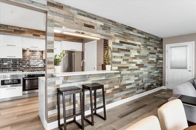436 Yorktown Ct, Aurora, IL 60504 - bar with appliances with stainless steel finishes, tasteful backsplash, baseboards, and light wood-type flooring