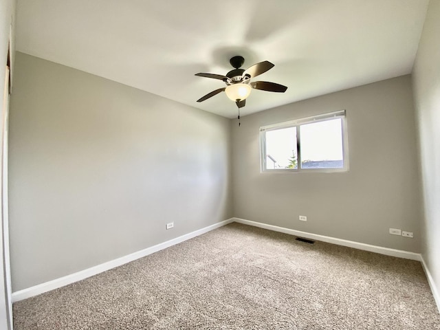 carpeted spare room featuring a ceiling fan and baseboards