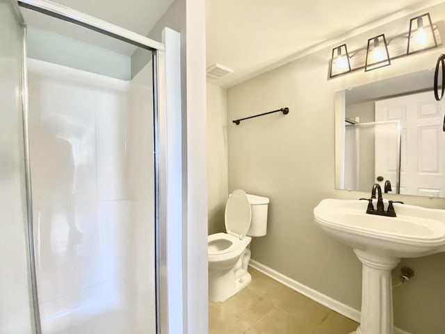 bathroom featuring baseboards, a shower stall, toilet, and tile patterned floors