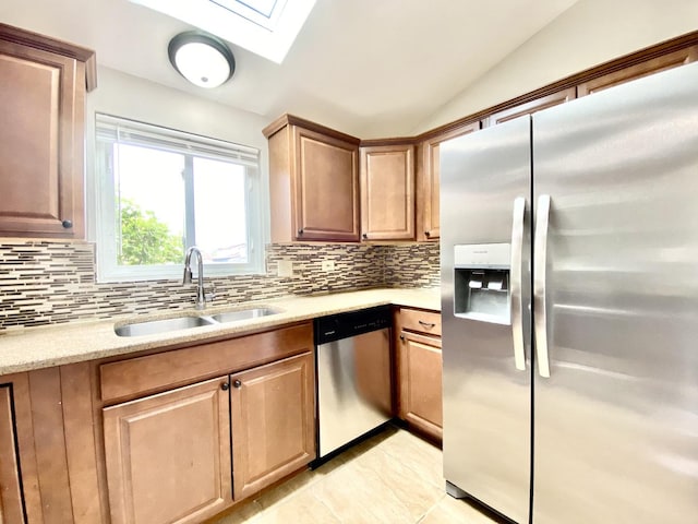 kitchen with stainless steel appliances, a sink, a skylight, decorative backsplash, and lofted ceiling