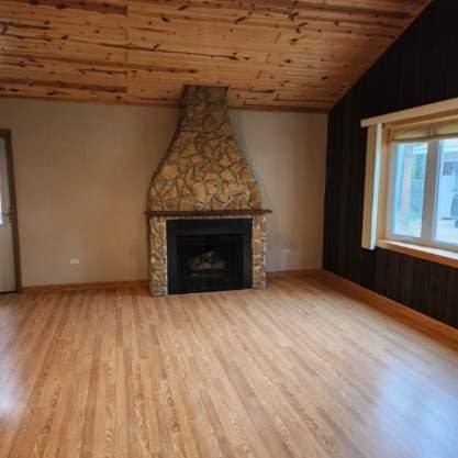 5900 W 110th St, Chicago Ridge, IL 60415 - unfurnished living room featuring wood finished floors, vaulted ceiling, wood ceiling, baseboards, and a stone fireplace