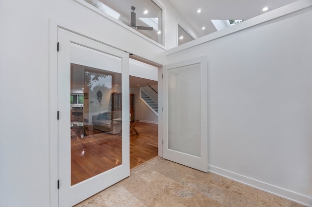 doorway with stairs, baseboards, stone finish floor, recessed lighting, and a skylight