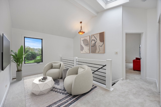 sitting room with carpet floors, baseboards, and vaulted ceiling with skylight