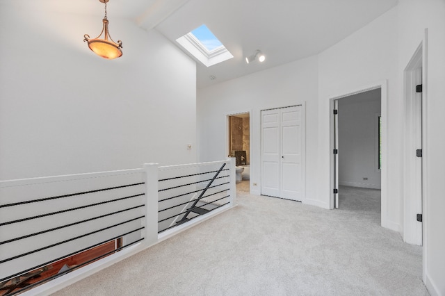 hallway with a skylight, beam ceiling, carpet floors, high vaulted ceiling, and an upstairs landing