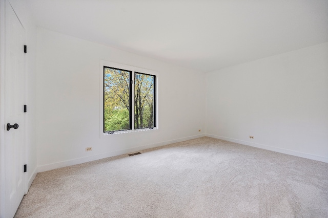 spare room with light colored carpet, baseboards, and visible vents