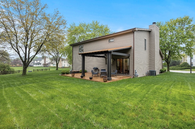 back of house with a yard, a patio, cooling unit, and a chimney