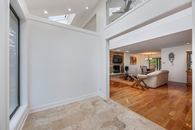 entryway with light wood-style floors, a skylight, a fireplace, baseboards, and an inviting chandelier