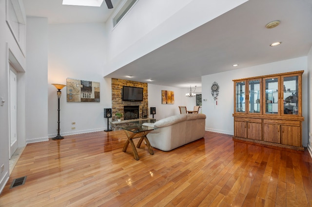 living area featuring visible vents, light wood-style floors, baseboards, a stone fireplace, and recessed lighting
