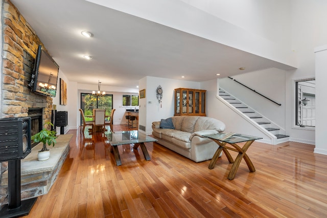 living area featuring a fireplace, baseboards, stairway, a chandelier, and light wood finished floors