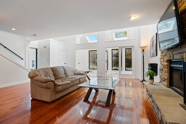 living area featuring wood-type flooring, a fireplace, baseboards, stairway, and recessed lighting
