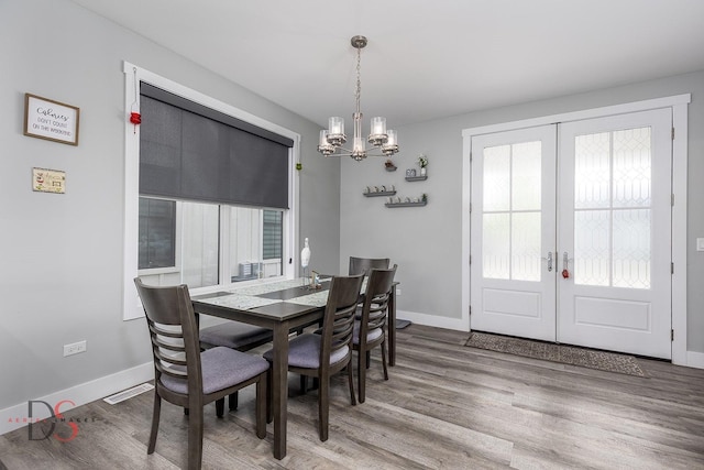 dining area with a notable chandelier, french doors, baseboards, and wood finished floors