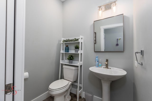 half bathroom featuring toilet and baseboards