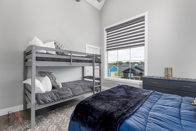 bedroom with baseboards, high vaulted ceiling, and wood finished floors