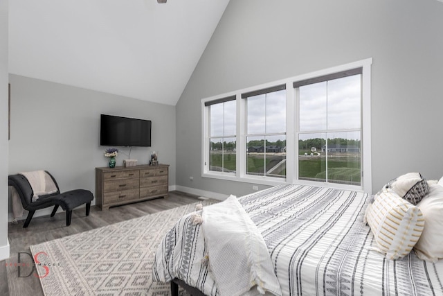 bedroom with baseboards, high vaulted ceiling, and wood finished floors