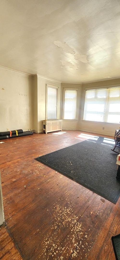 7943 S Vernon Ave, Chicago, IL 60619 - unfurnished living room featuring healthy amount of natural light, hardwood / wood-style flooring, and crown molding