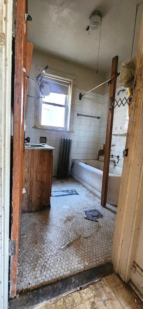7943 S Vernon Ave, Chicago, IL 60619 - bathroom with washtub / shower combination, radiator heating unit, and vanity