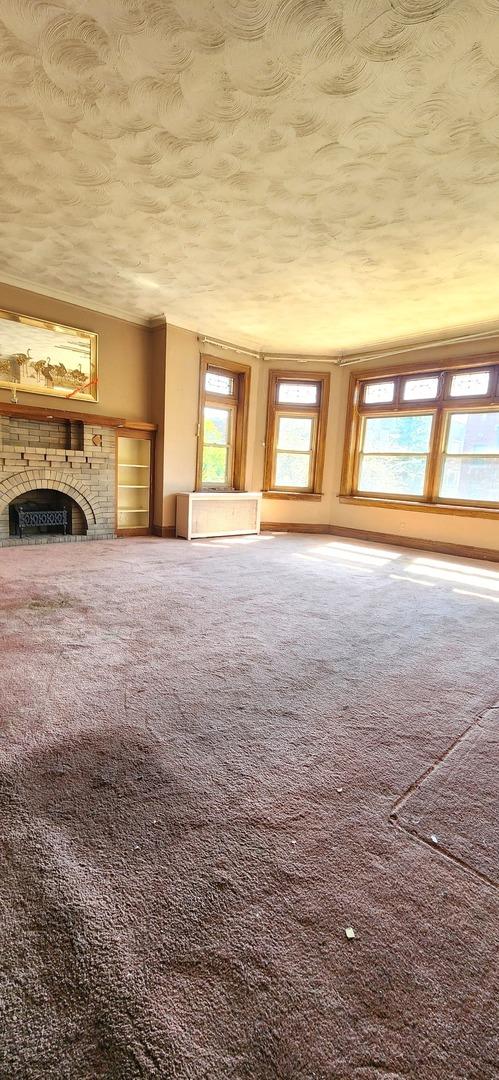 7943 S Vernon Ave, Chicago, IL 60619 - unfurnished living room featuring carpet flooring, a fireplace, and a textured ceiling
